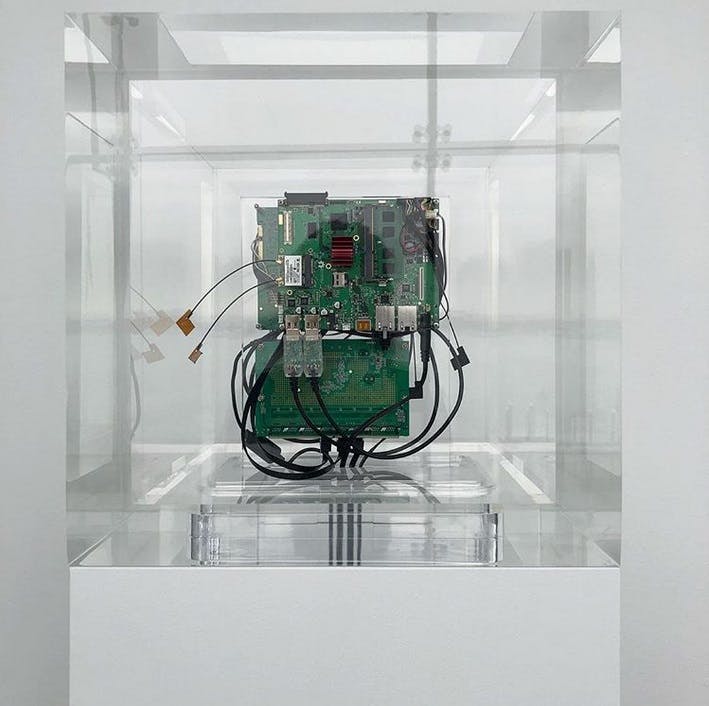 Image of the interior of a device in a glass cube on a white podium, against a white wall.
