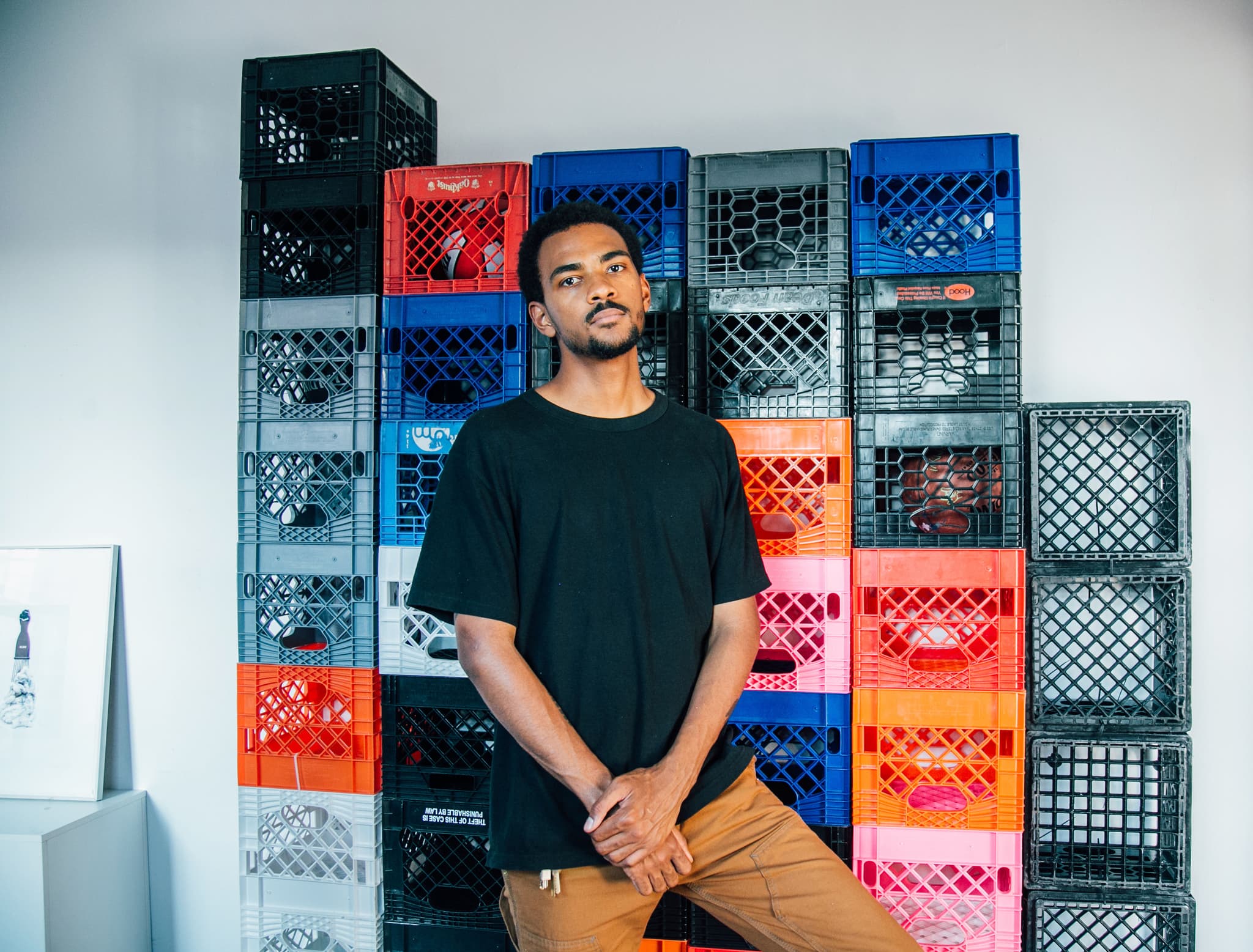 Shaka Dendy sits in front of multi-colored, stacked crates.