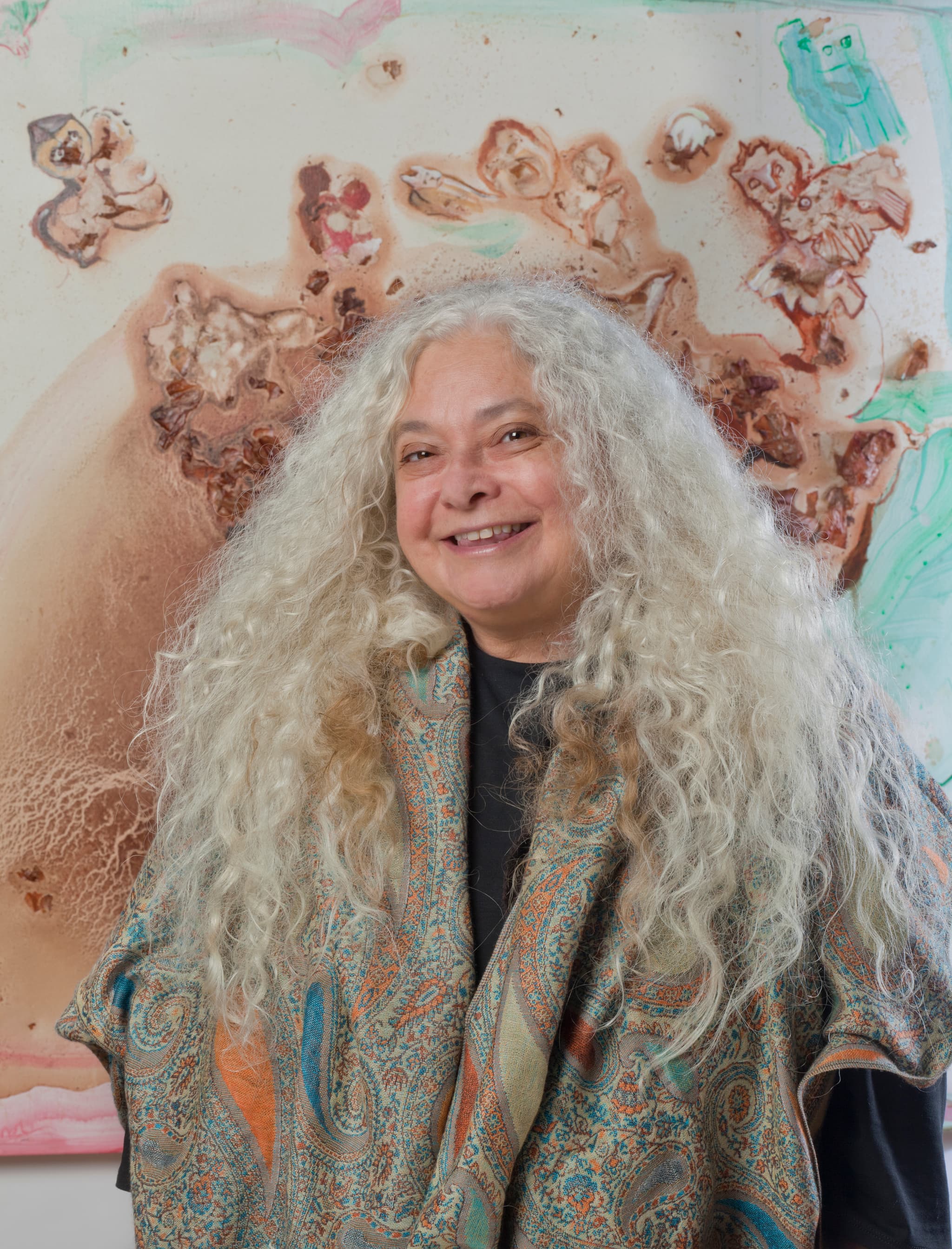 A portrait of Marsha Nouritz Odabashian in front of a work of art.