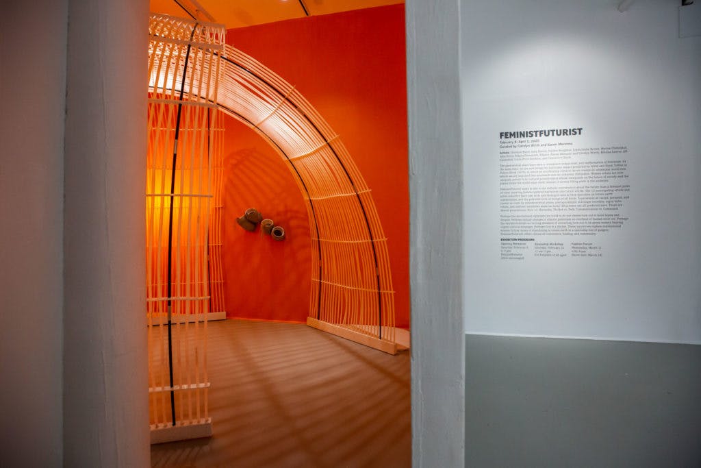 The orange glow of an installation lights the exhibition space in the FeministFuturist show.