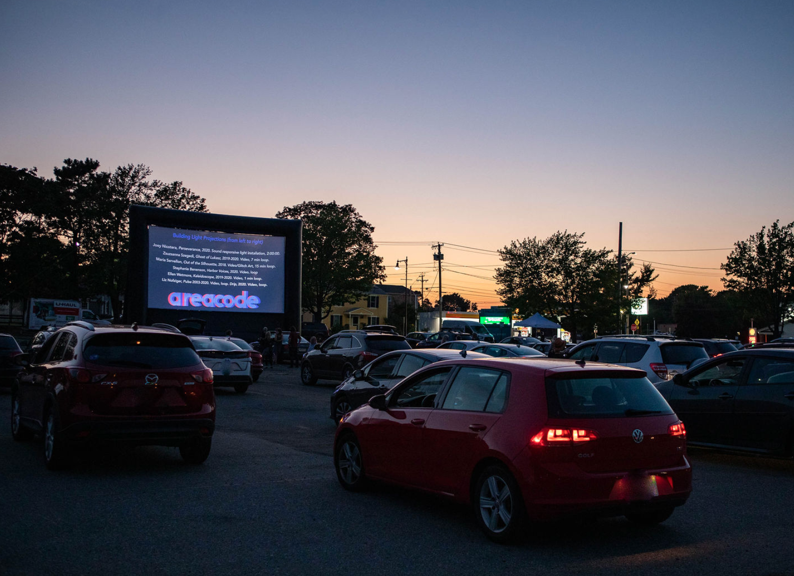 Cars are parked in front of a pop-up screen displaying a message at Salem State University.