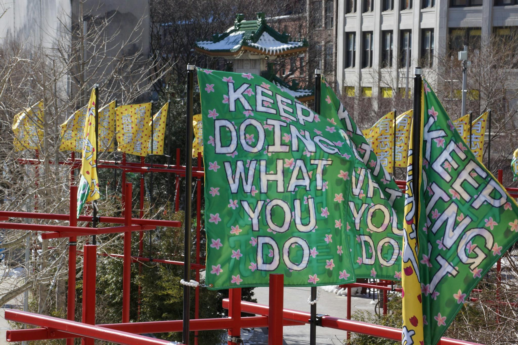 A green banner reading "Keep Doing What You Do" is part of a public artwork by Andy Li.