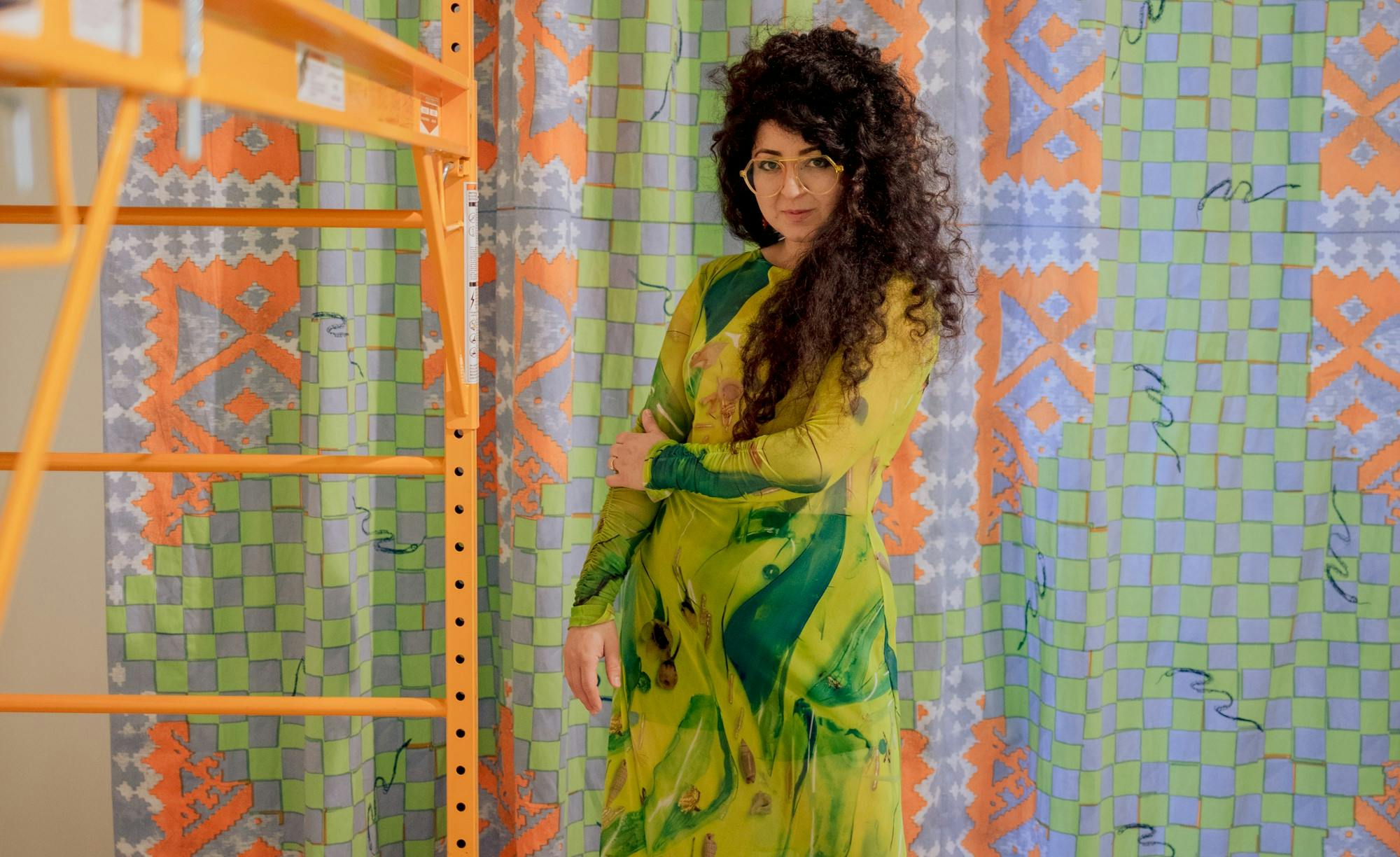 A portrait of Sheida Soleimani wearing a green dress during an exhibit installation.