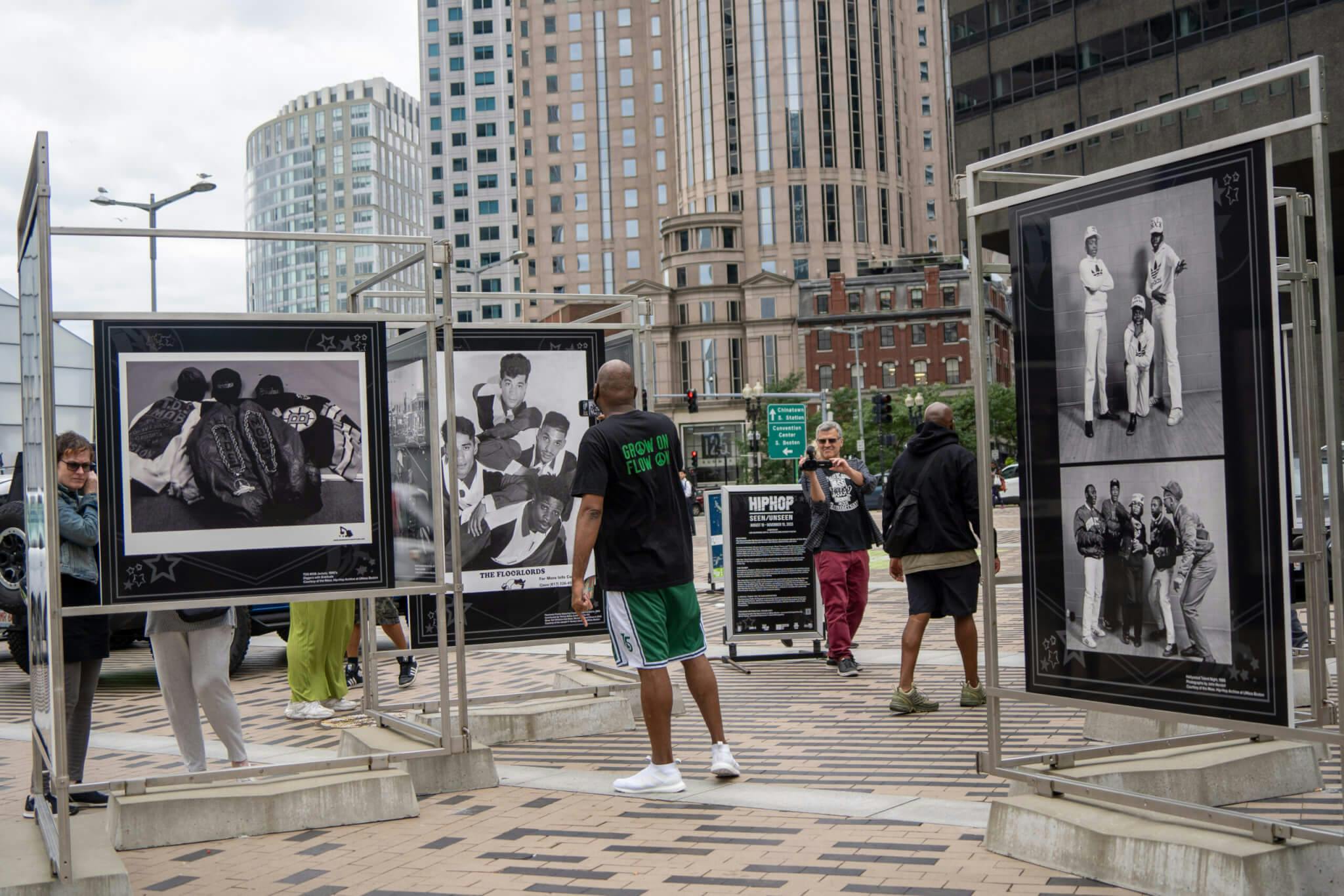 Installation view of “Hip-Hop: Seen/Unseen" at Dewey Square Plaza on The Greenway, with people looking at the photos on display