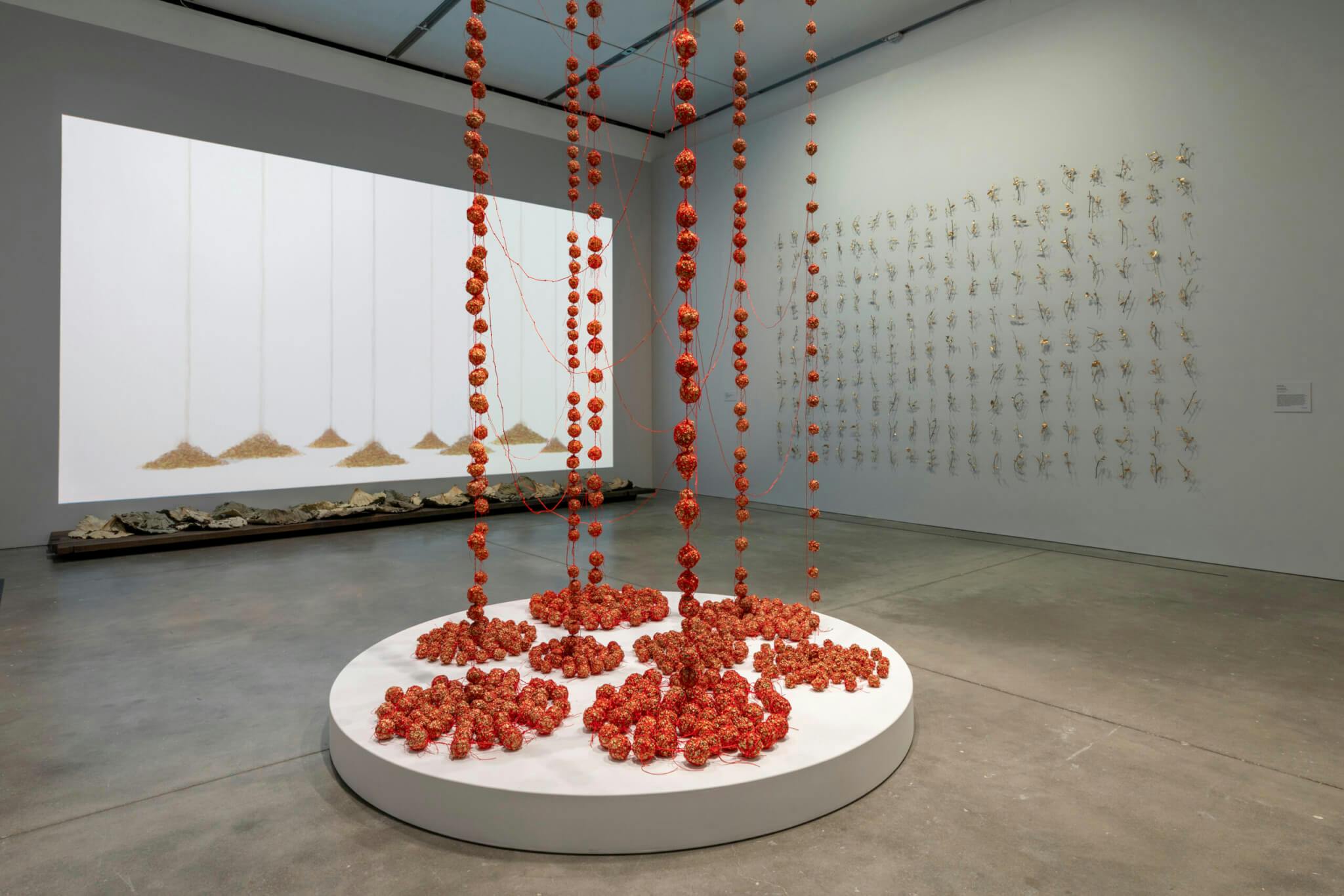 Dangling red strands form an installation by Yu-Wen Wu in the middle of a room.