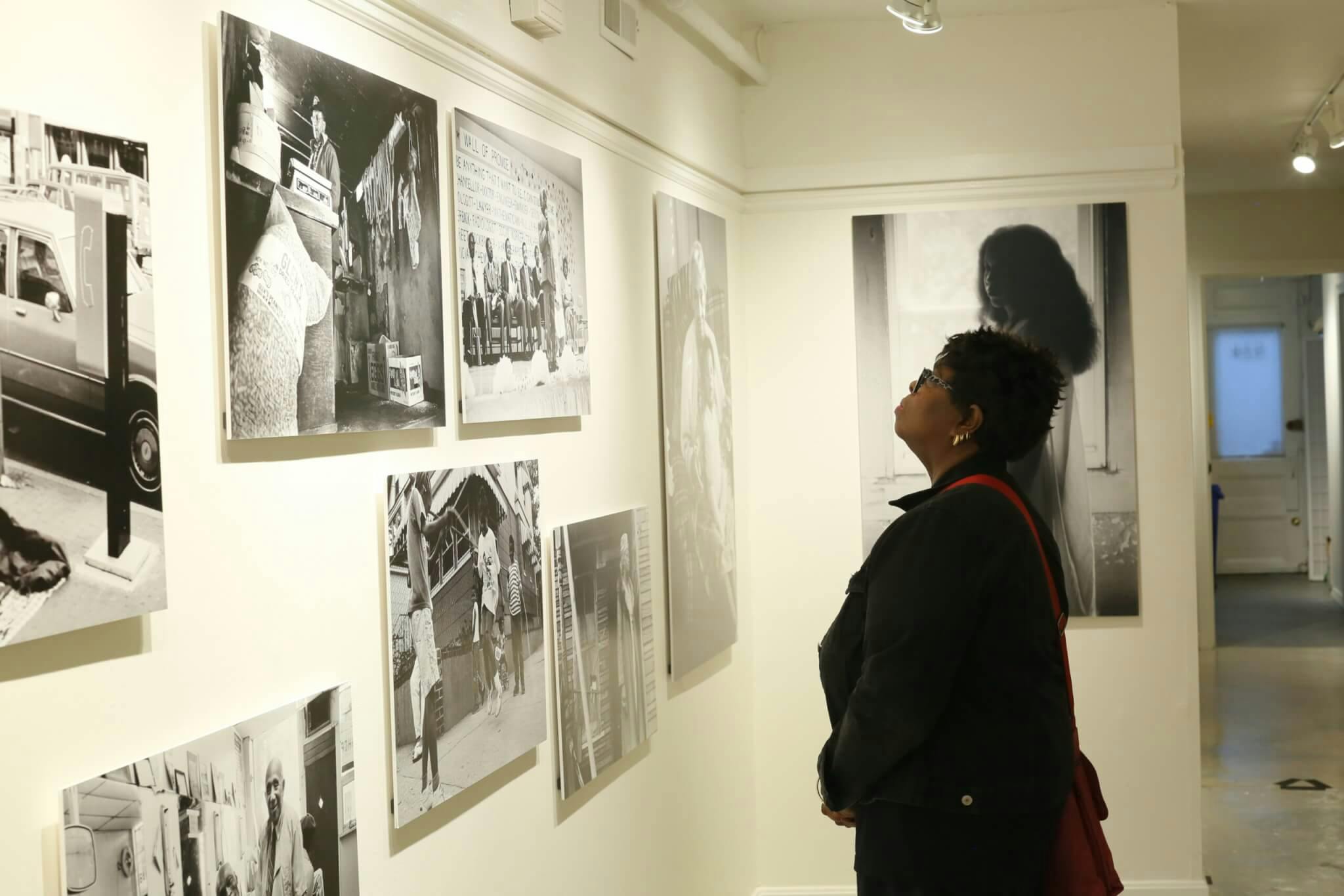 A woman stands in front of a wall of black and white photographs.