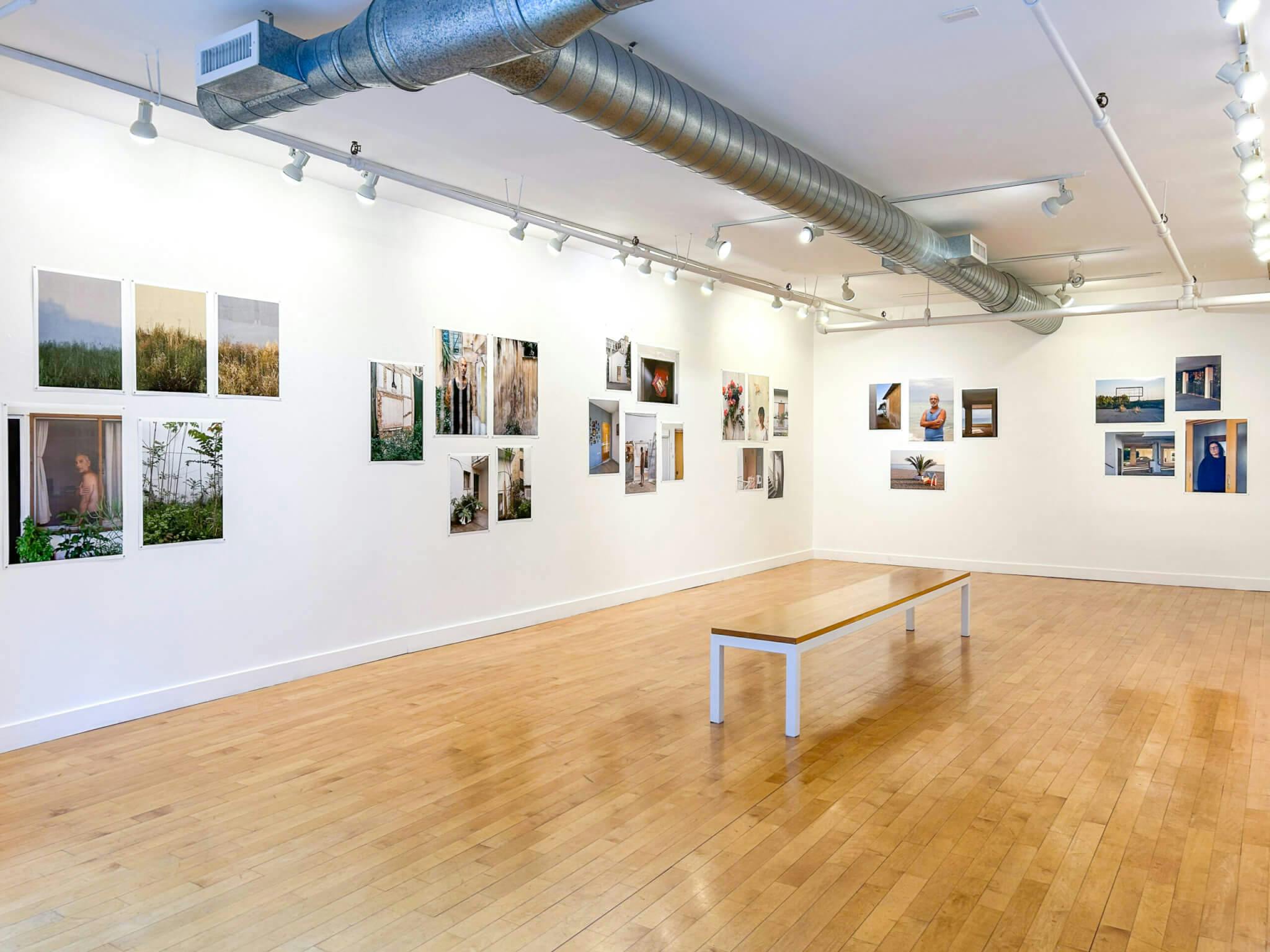 Photographs by Yorgos Efthymiadis, featuring scenes of nature and profiles of individuals, line the walls of the gallery.