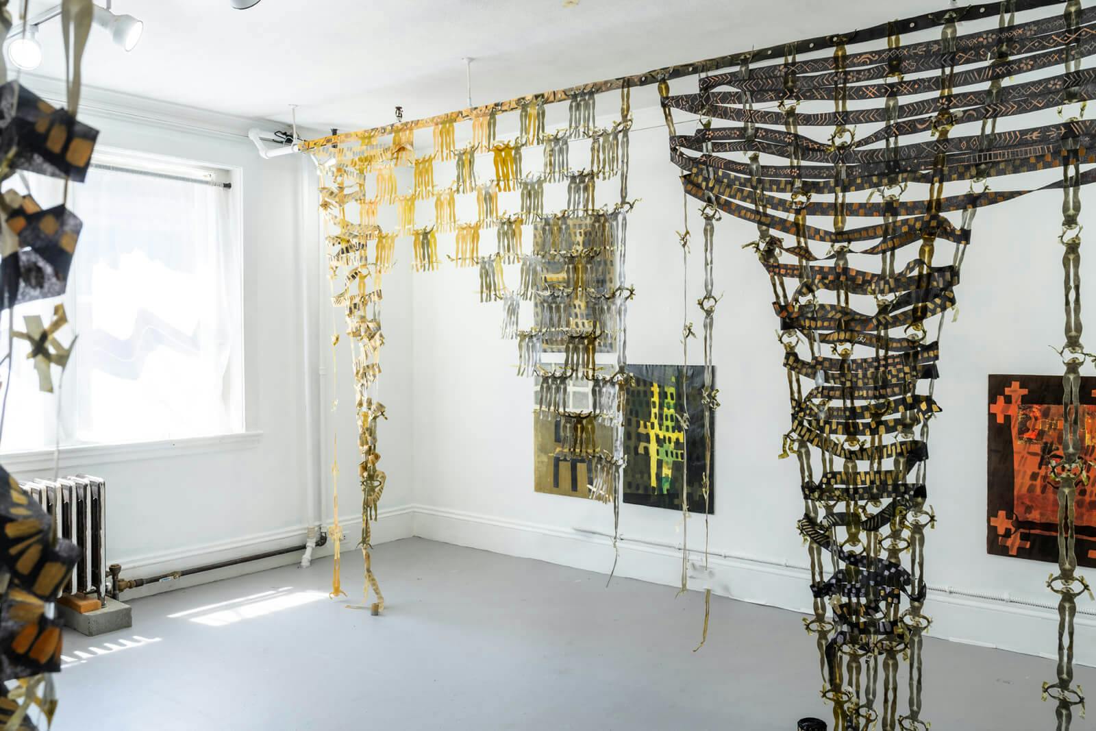 An installation features gold hangings suspended from the ceiling.
