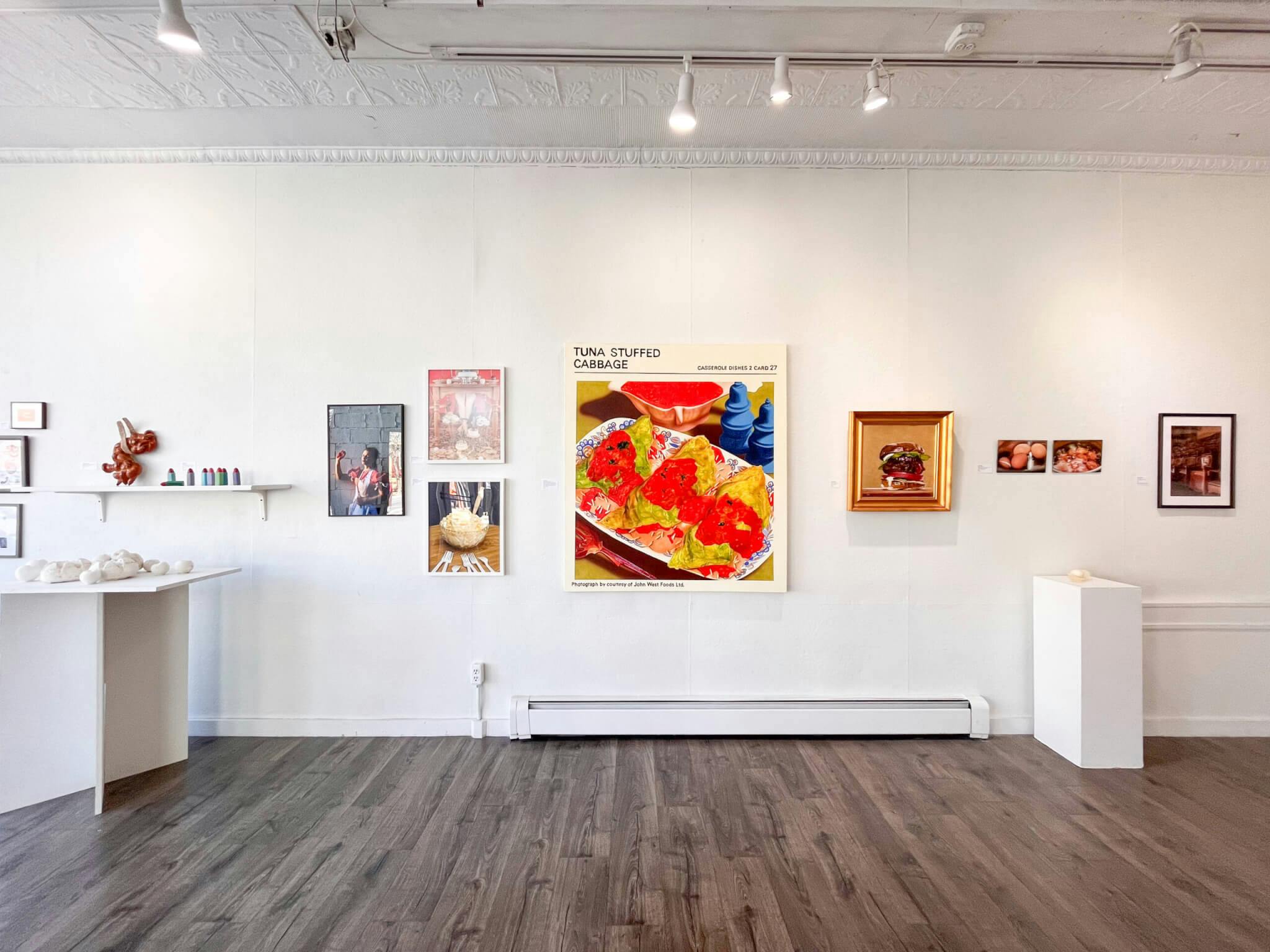 A set of artworks, the centerpiece featuring bright, bold colors, on display against a white wall at Gallery 263.