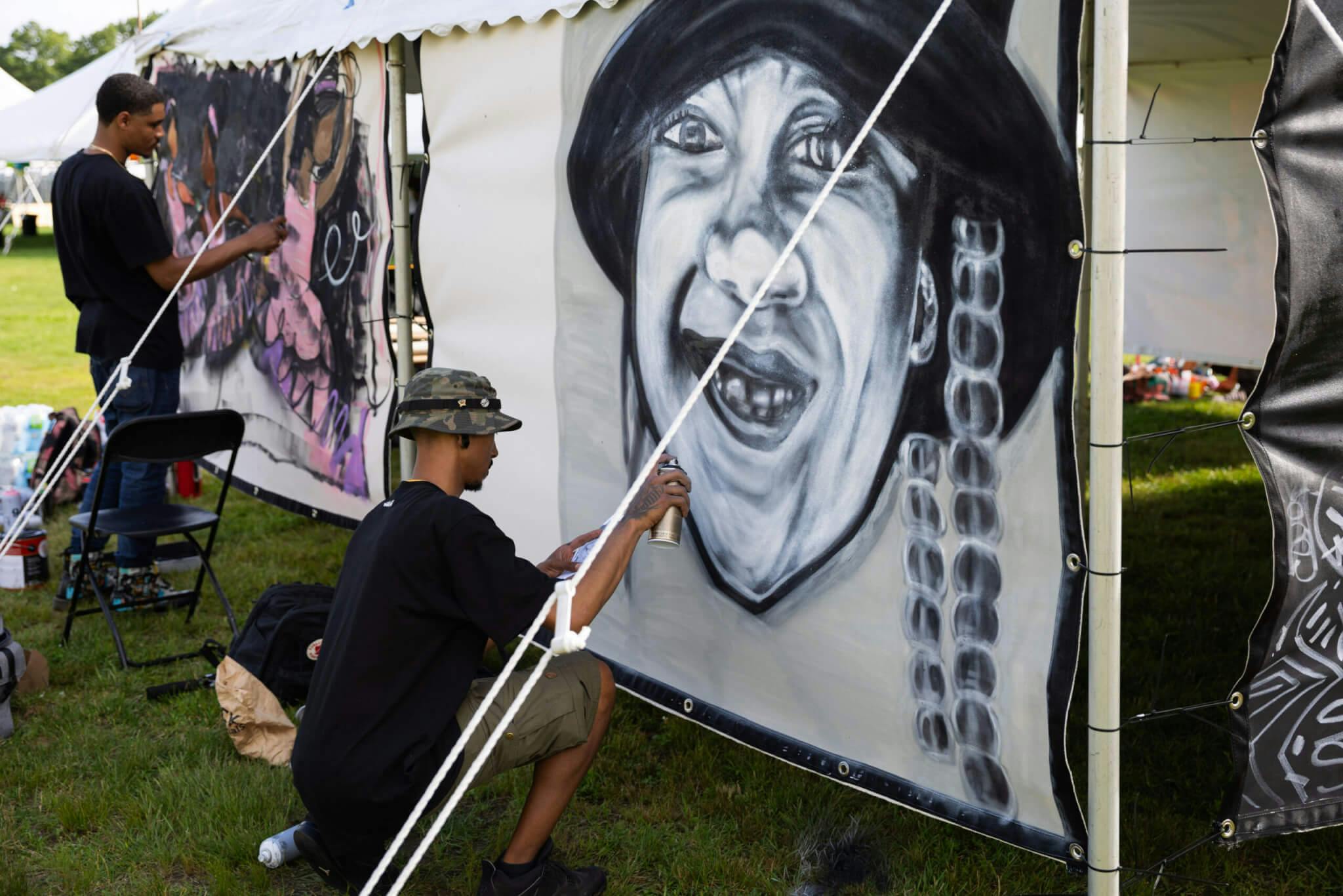 An artist works on a large graffiti mural at BAMS Fest.