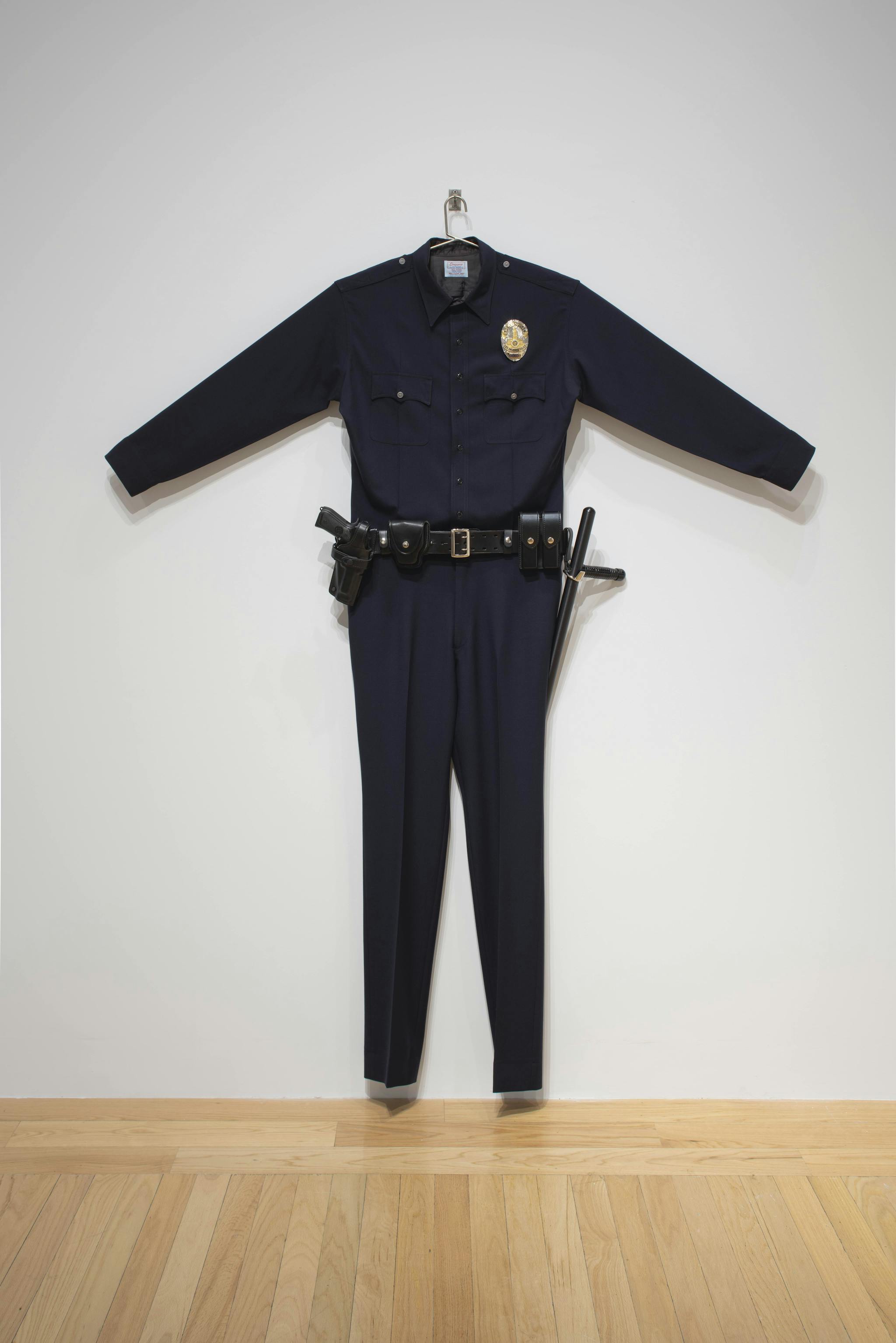 A navy blue police uniform by Chris Burden is on display.