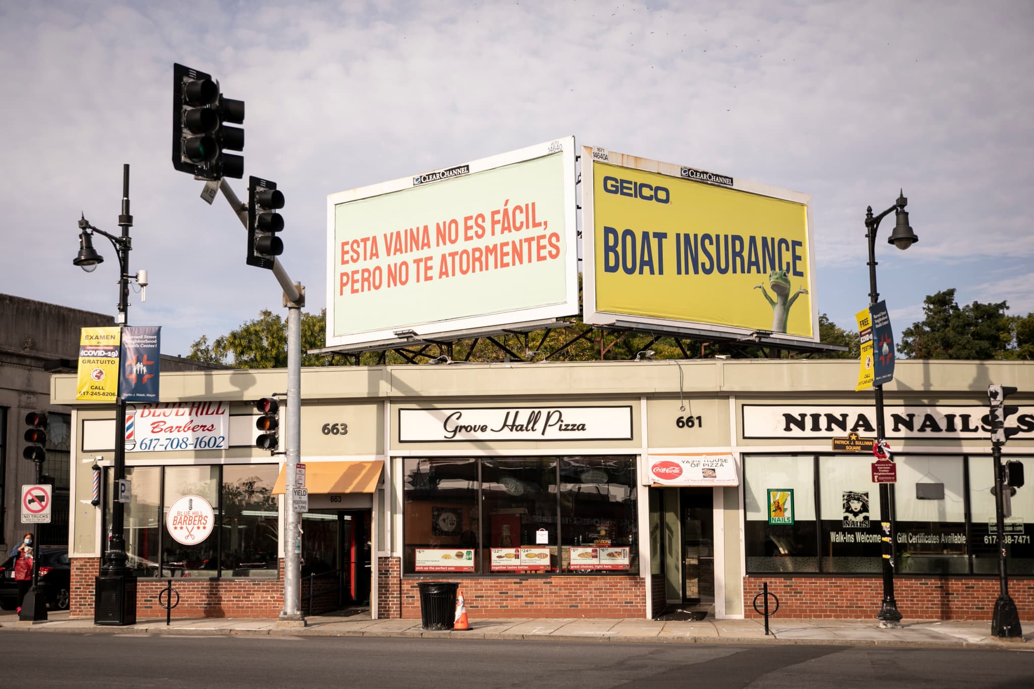 Gabriel Sosa's billboard, featuring Spanish text in orange, is positioned on top of Grove Hall Pizza.