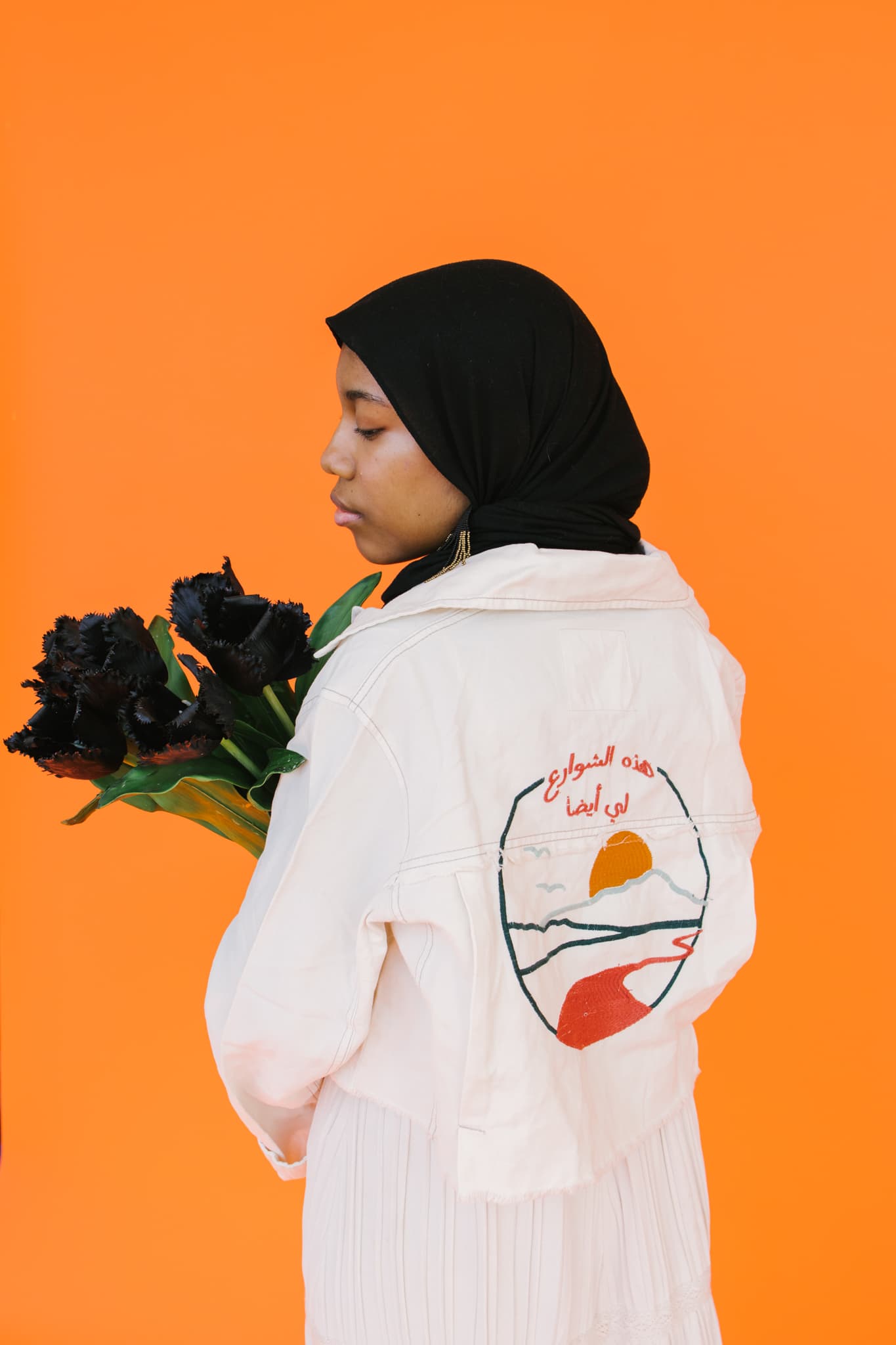 A portrait of Asiyah Herrera holding flowers with black petals.