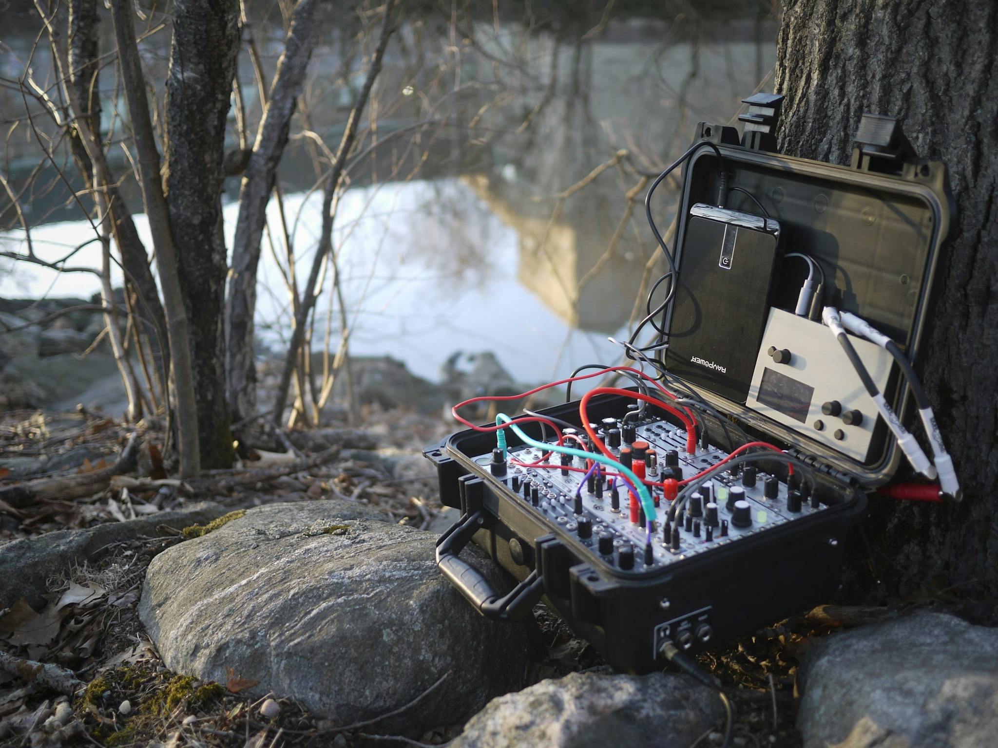 A sound system rests on rocks outside near the Mystic River.
