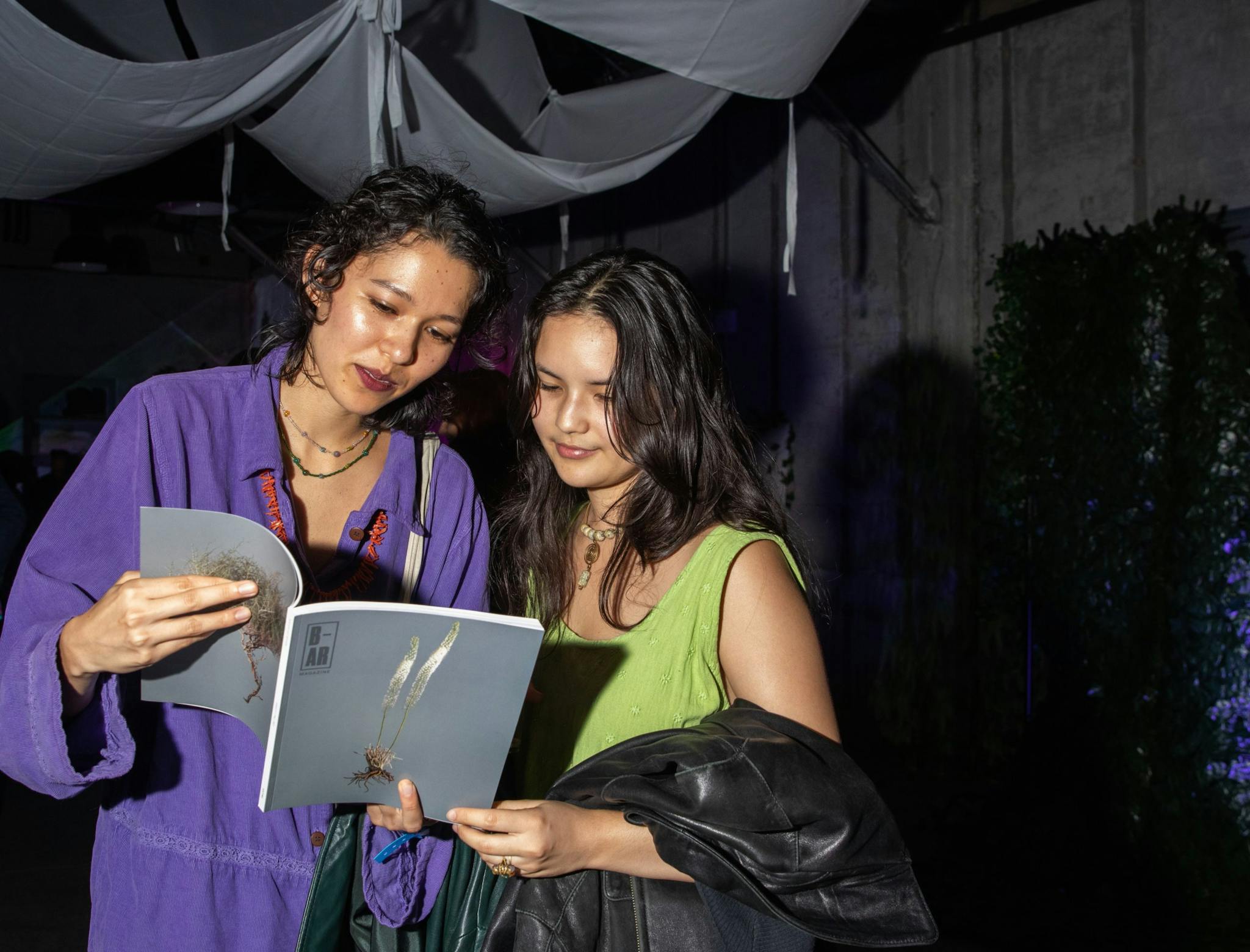 Two women read a copy of Boston Art Review Issue 07 while at the magazine's release party.