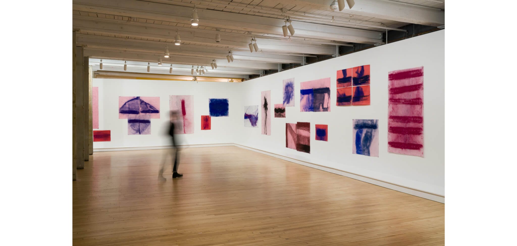 Works on paper by Jason Moran adorn the walls of a gallery, while the blurred figure of a visitor appears in the center of the room.