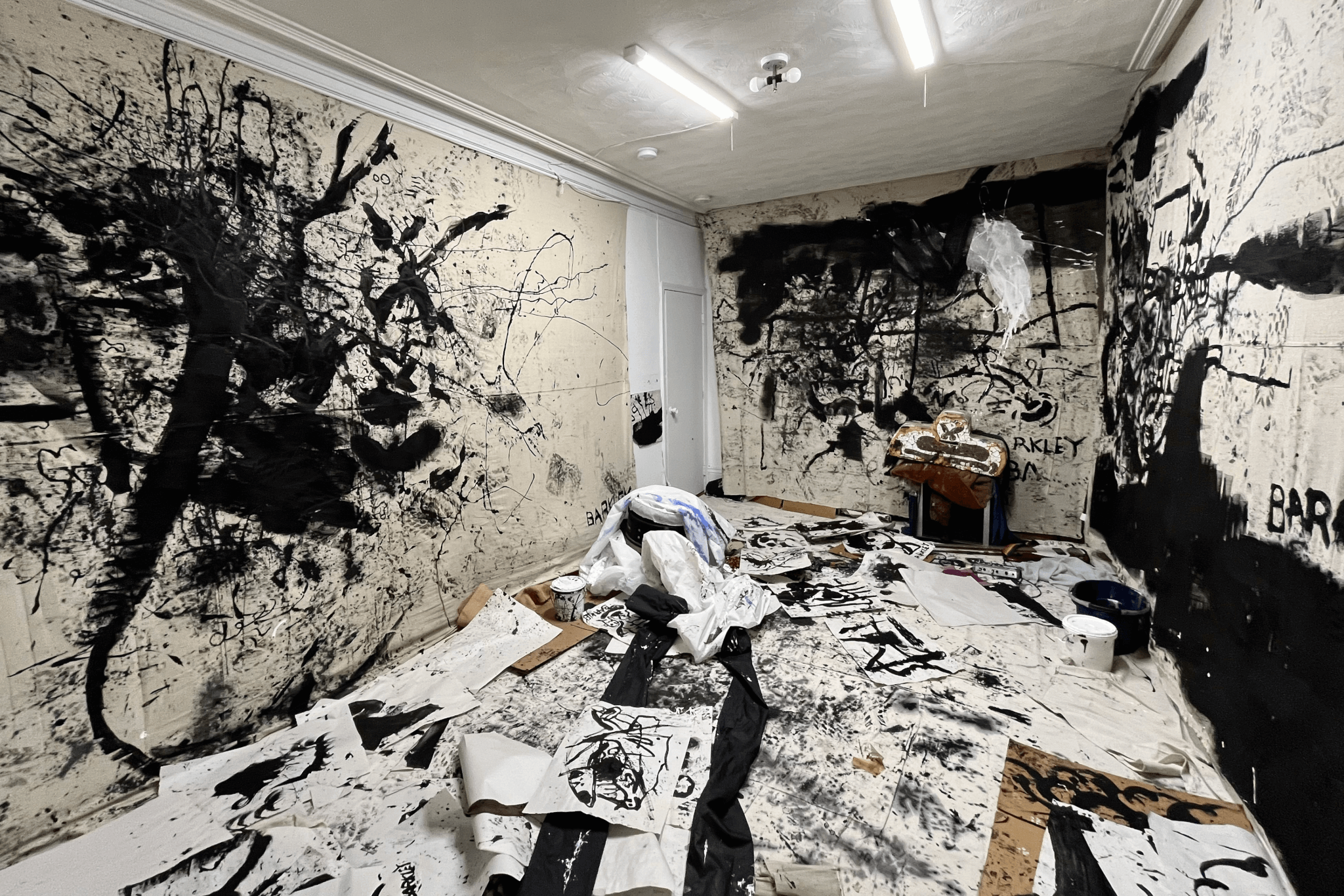 The walls and floors of a room are covered with splatters of black paint.