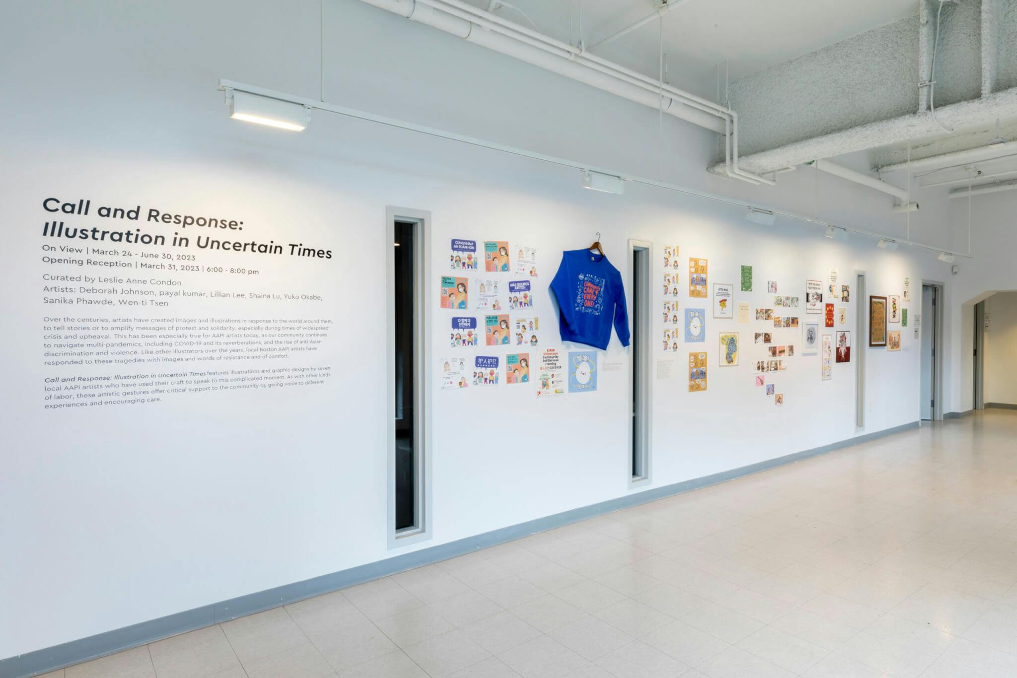 A bright blue sweatshirt hangs against a white wall at Pao Arts Center, beside other assorted images.