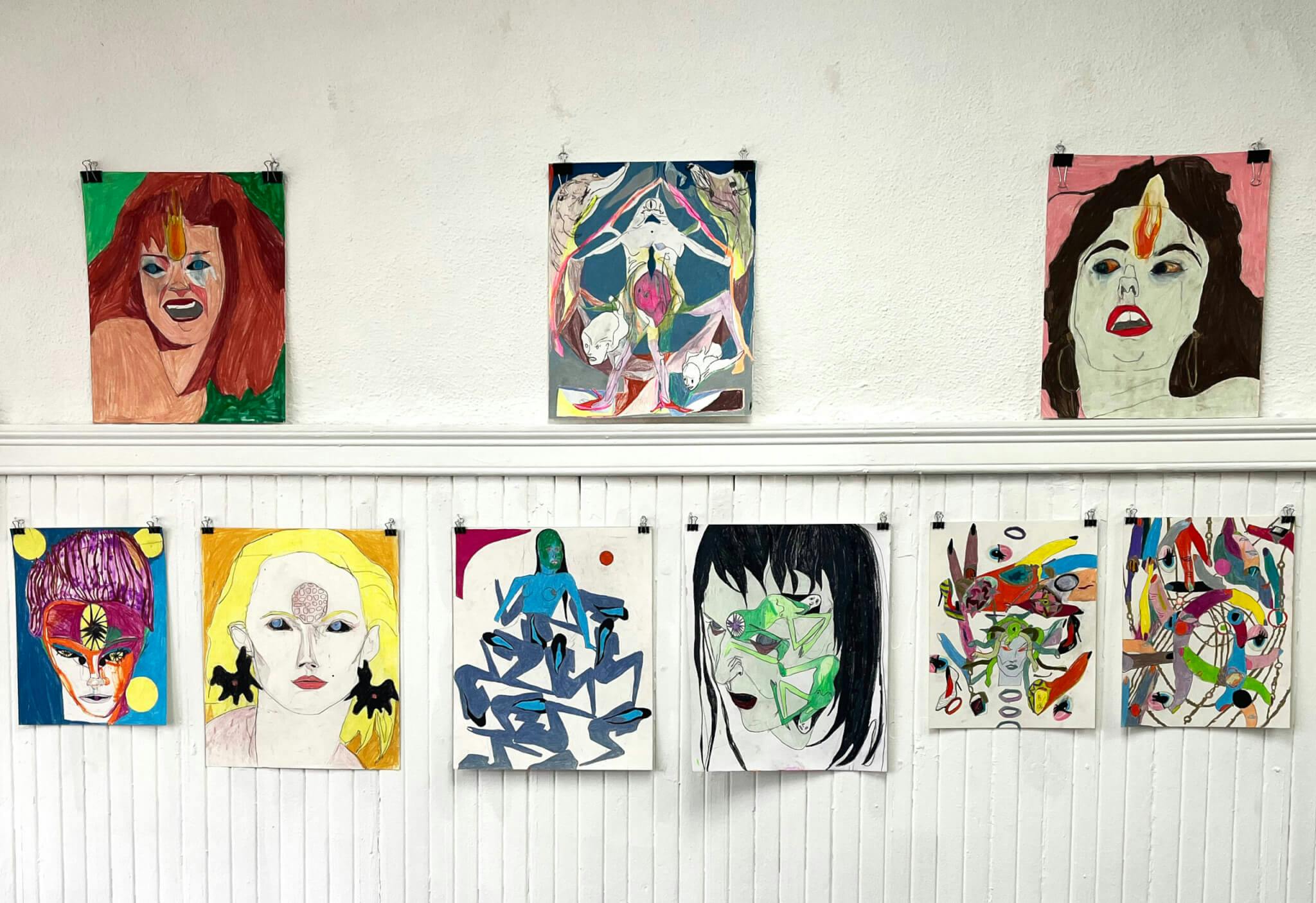 Colorful designs, many of faces, adorn the white walls of Shoe Bones Gallery.