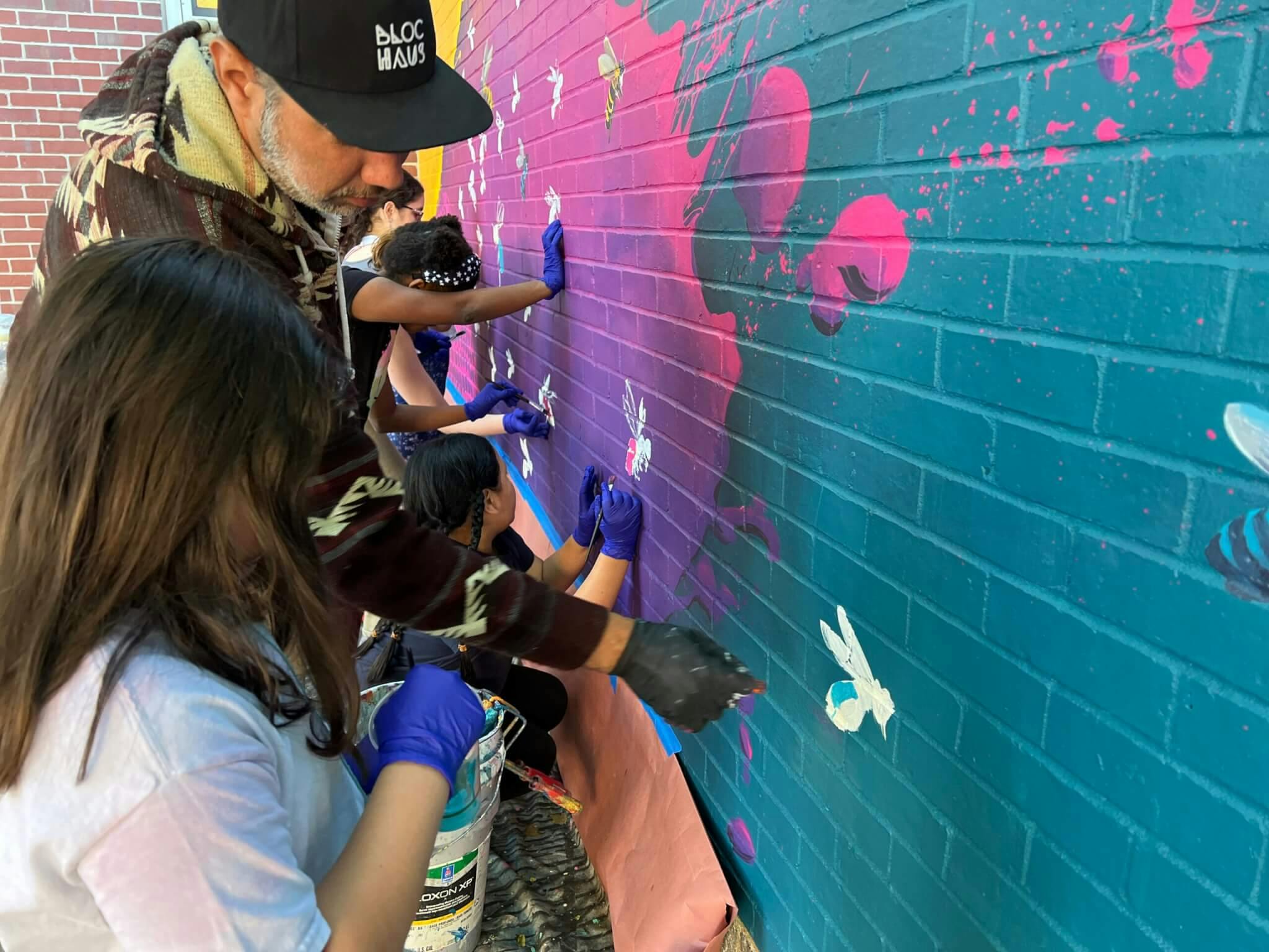 Image of Felipe Ortiz helping students at the Dante Alighieri Montessori School paint a mural in East Boston