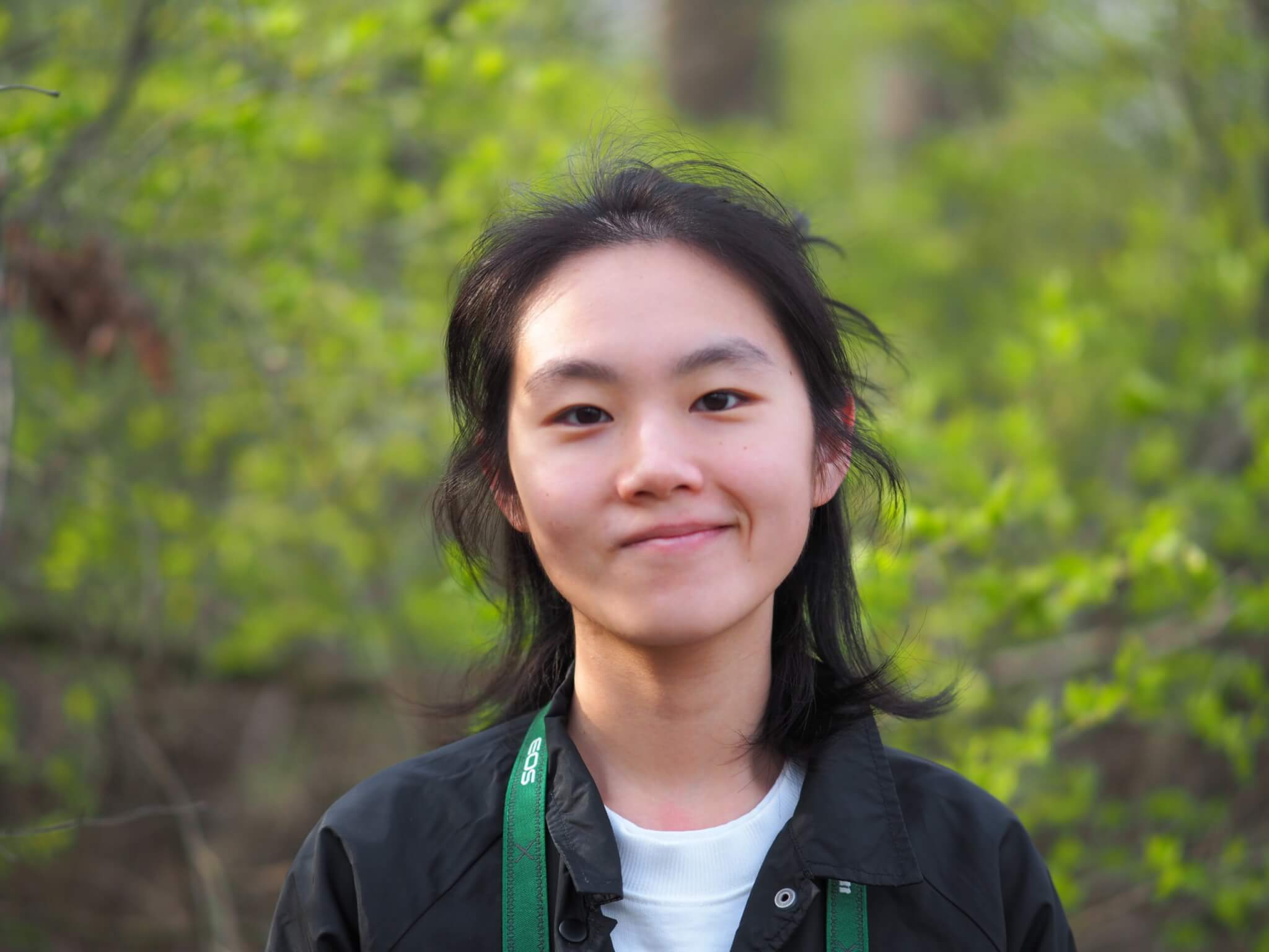 A headshot of Lilan Yang, posed in front of a leafy tree.