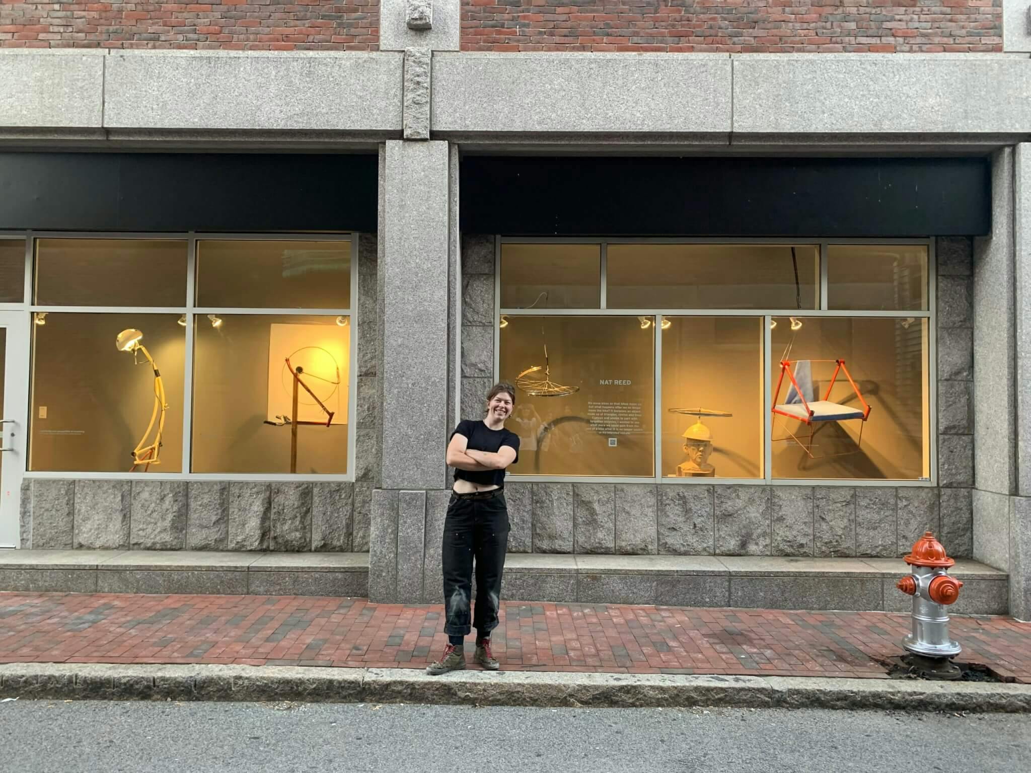 Image of artist Nat Reed in front of "Bikes Move Us" installation