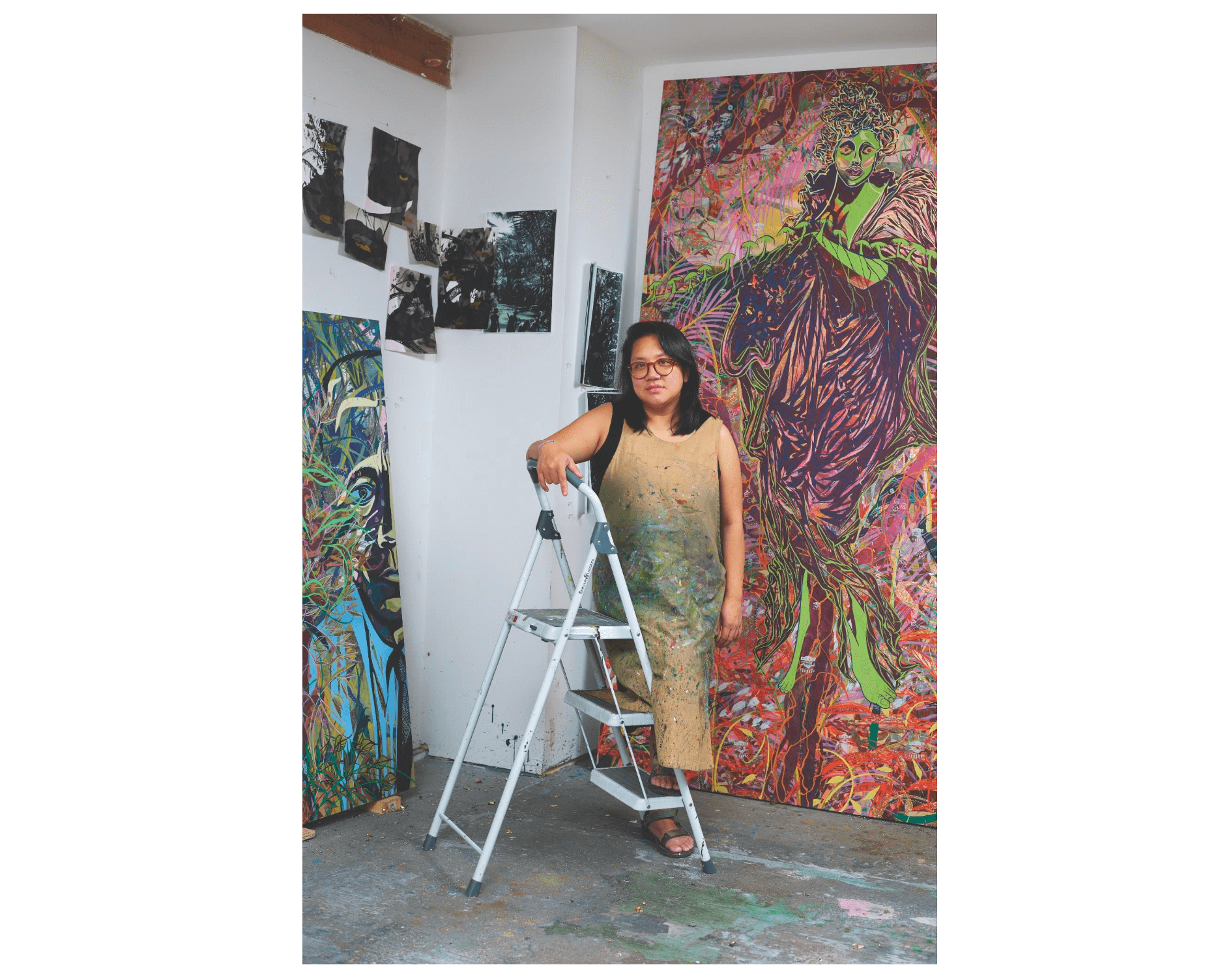 Tammy Nguyen stands by a ladder in her Connecticut studio, positioned in front of a large work of art.