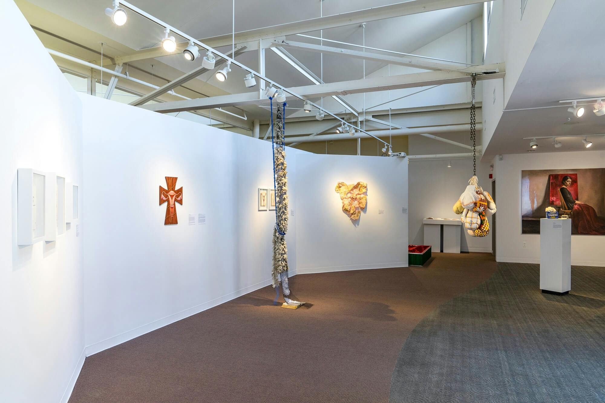 Sculptures linked together by the theme of reproductive justice are suspended from the ceiling.