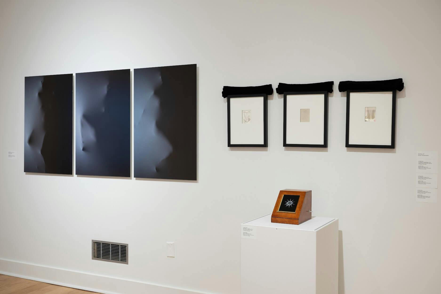 Artworks conveying embodied femininity, set against the white wall of a gallery, at Fitchburg Art Museum.